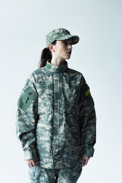 military woman with ukrainian chevron looking away isolated on grey - Foto, Imagem