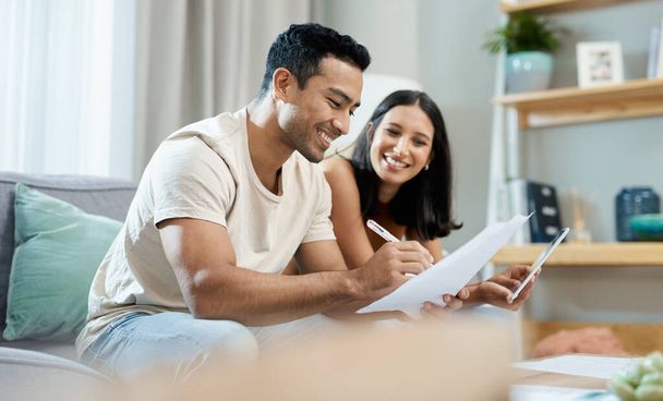 Were doing so well with our finances. a young couple sitting together in their living room at home and calculating their finances - Foto, imagen
