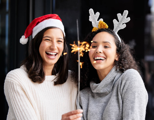 Christmas is the day that holds all time together. two friends using a sparkle stick ay home - Foto, Imagem
