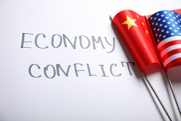 USA and China flags near words ECONOMY CONFLICT on white background - Foto, imagen