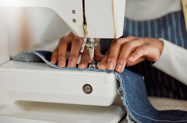 Close up hands of a professional female designer sitting on a sewing machine in her studio. Process of a tailor at work on repairing and designing clothes. Casual alterations being done to jeans - Foto, immagini
