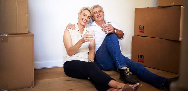 May your home be as happy as ours is. a mature couple toasting with water after a successful day moving house - Fotografie, Obrázek