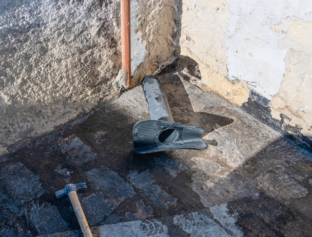 Werknemer plaatst een PVC hoes met snelinstellende mortel voor het aftappen van regenwater vanaf een vlak terras. - Foto, afbeelding