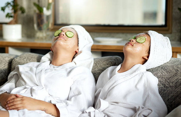 Beauty, relaxing and skincare for mother and daughter, having a spa treatment at home. Little girl and parent bonding while doing hygiene, refreshing grooming. Females with cucumber, facial mask. - Φωτογραφία, εικόνα