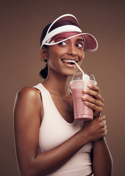 My daily dose of vitamins all in a cup. an attractive young woman standing alone in the studio and drinking a smoothie - Photo, Image