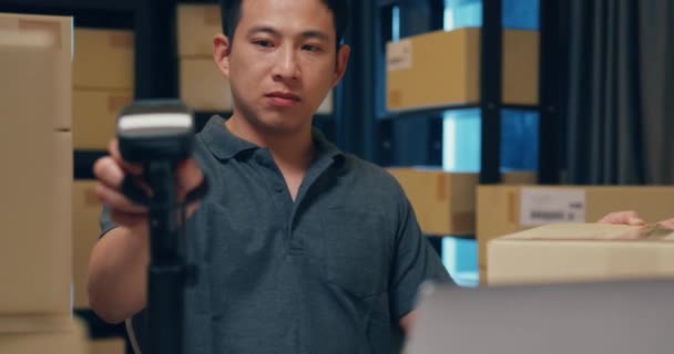 Close-up Asian businessman use barcode machine scan customer data in paper box and type register online information order detail in laptop for express delivery at warehouse. Startup business concept. - Filmmaterial, Video