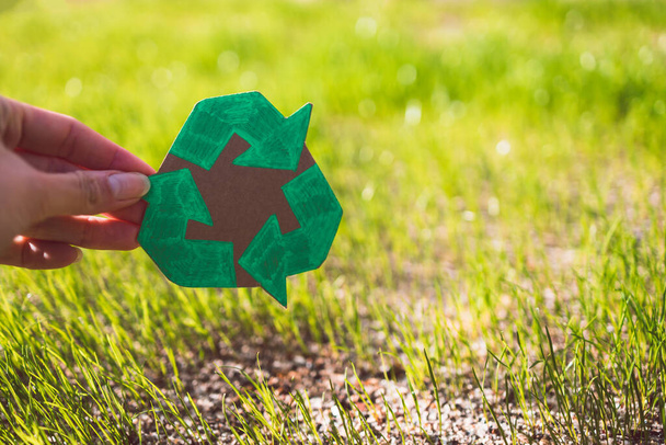 recycle sign hand drawn on cardboard over green grass under the sunshine - Φωτογραφία, εικόνα