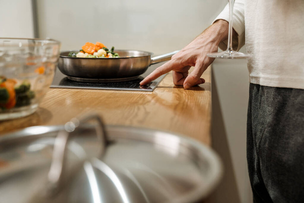 European man making dinner with vegetables in kitchen at home - Foto, Bild