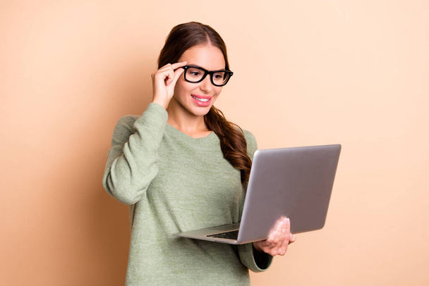 Photo of confident sweet girl dressed green pullover hand eyewear working modern device isolated beige color background. - Photo, image