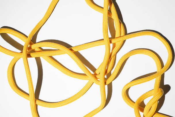 Yellow rope isolated on white background. Messy fabric cable or twine in sunshine with harsh shadow. Creative texture backdrop for design. Colorful string. Close up - Photo, image