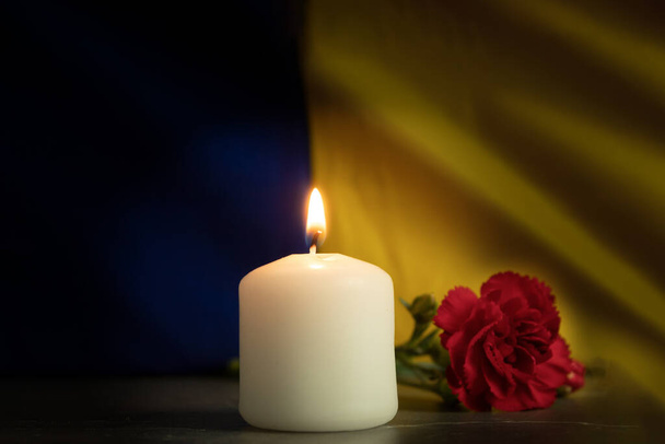 Una vela encendida en el fondo de la bandera nacional de Ucrania. Fondo con espacio de copia. Vela conmemorativa, memoria y dolor - Foto, Imagen
