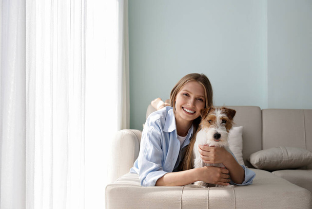 Portrait of young beautiful woman spending time with her adorable wire haired Jack Russel terrier puppy at home. Female with rough coated pup. Interior background, close up, copy space. - Valokuva, kuva