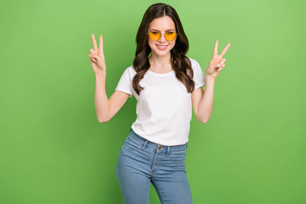 Photo of adorable sweet young lady wear white t-shirt glasses showing two thumb up isolated green color background. - Foto, imagen
