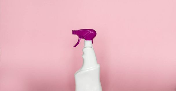 White plastic spray bottle for liquid cleaning products isolated on pink background. Packaging mockup bottle with violet sprayer - Foto, imagen