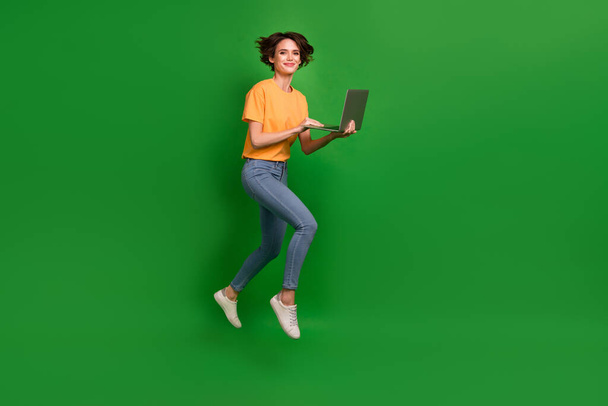 Full body profile photo of attractive lady jump hands hold use wireless netbook isolated on green color background. - Valokuva, kuva