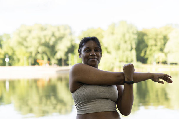 Plus kokoinen Afrikkalainen Amerikkalainen nainen venyttely puistossa kesäpäivänä  - Valokuva, kuva