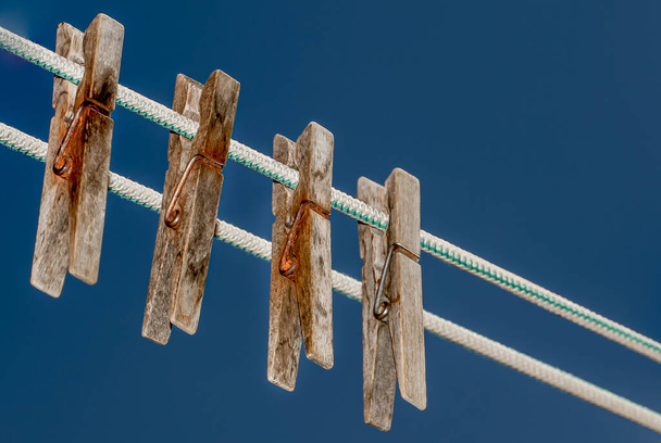 Дерев'яні прищіпки закріплені на мотузці з блакитним небом на фоні. дерев'яні прищіпки
 - Фото, зображення