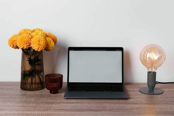 Blank screen laptop and vase with dahlia flowers on table. Home office concept. Designated work from home area. Close up, copy space, background. - Zdjęcie, obraz