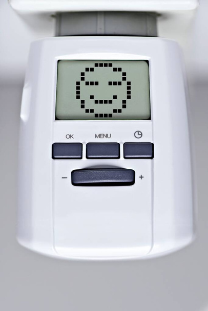 Digital thermostat of an heating radiator with smiley face. Heat and energy concept. - Fotografie, Obrázek