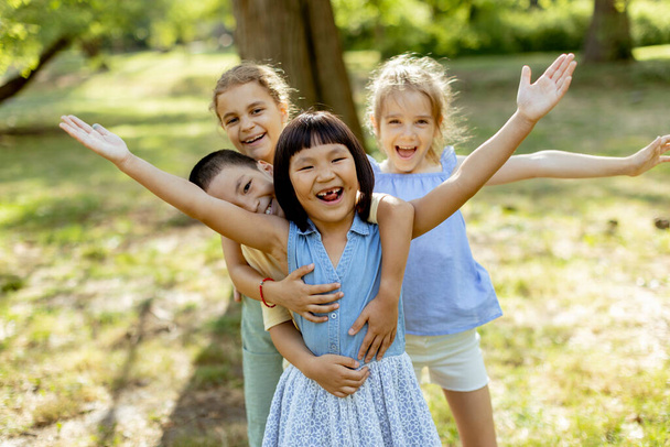 Group of cute asian and caucasian kids having fun in the park - 写真・画像