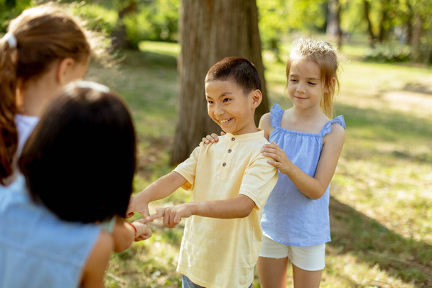 Group of cute asian and caucasian kids having fun in the park - Photo, Image