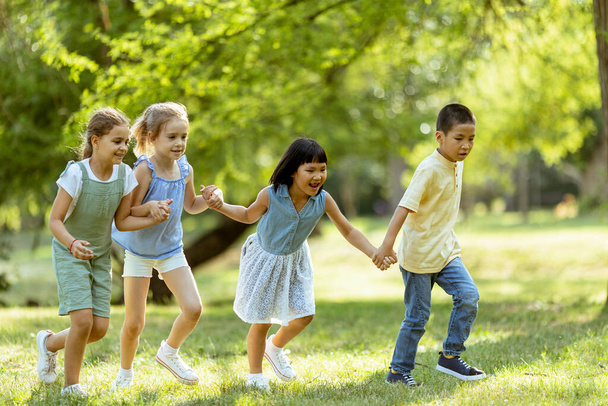 Group of cute asian and caucasian kids having fun in the park - Photo, Image
