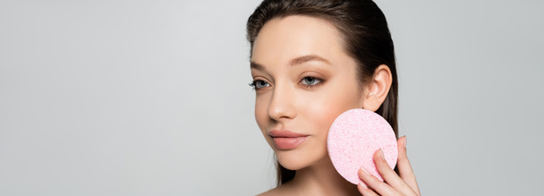 young woman holding exfoliating sponge isolated on grey, banner - Foto, immagini