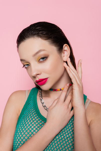 young woman with makeup posing while looking at camera isolated on pink  - Foto, Imagem