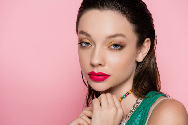 young brunette model with bright makeup looking at camera isolated on pink  - Фото, изображение