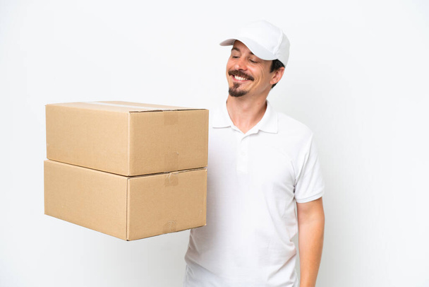 Delivery caucasian man isolated on white background looking to the side and smiling - Photo, Image