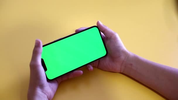 green screen. The child is holding a Smartphone in hand Close-up playing a game. phone with blank green screen mock up display for advertising. Slow motion. - Filmati, video