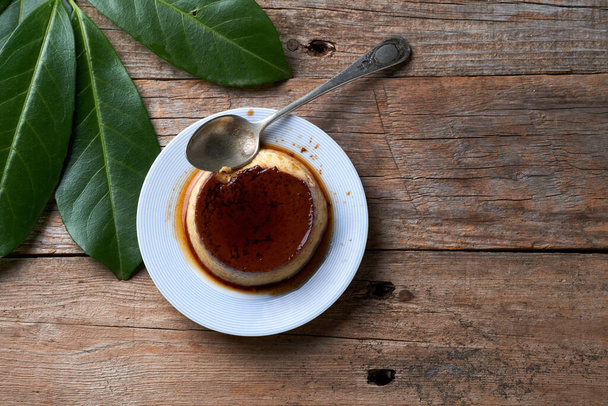 Crèmekaramelpudding met karamelsaus in bord op rustieke tafel - Foto, afbeelding