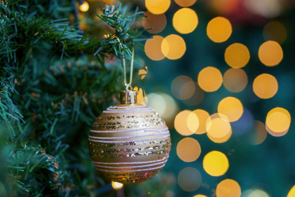 A glittered Christmas ball hanging on a tree against a bokeh background - Fotoğraf, Görsel