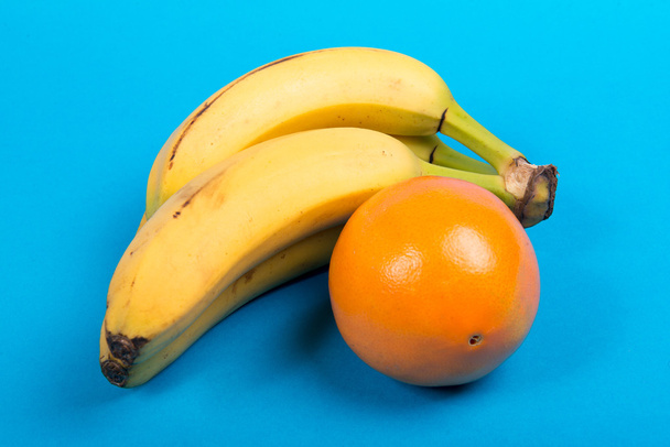 banana e uma laranja em um fundo azul
 - Foto, Imagem