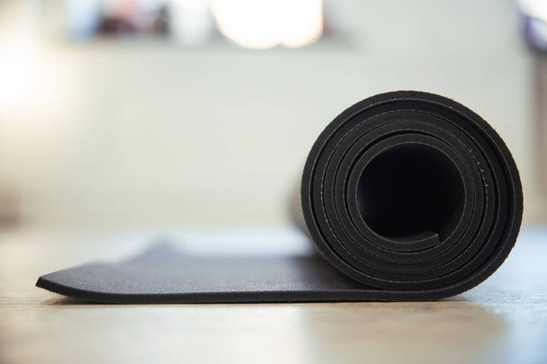 A closeup of a black yoga mat roll indoors - Фото, изображение