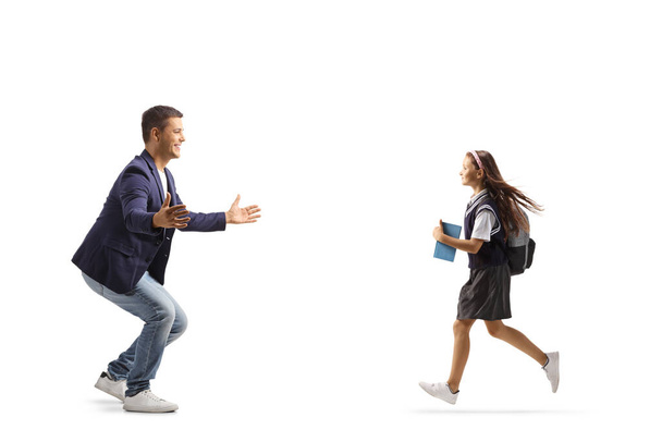 Full length profile shot of a schoolgirl running to hug her happy father isolated on white background - Foto, afbeelding