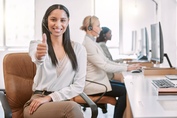 Solving problems one call at a time. Cropped portrait of an attractive young female call center agent wearing a headset and giving thumbs up while working in her office - Foto, immagini