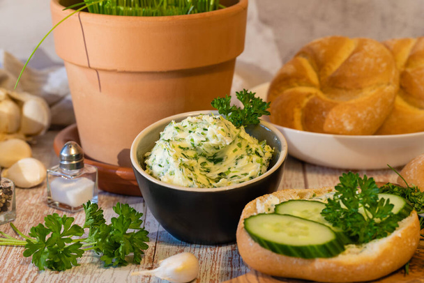 Spicy herb butter, fresh rolls and chopped herb ingredients on cutting board, close up. - Fotografie, Obrázek