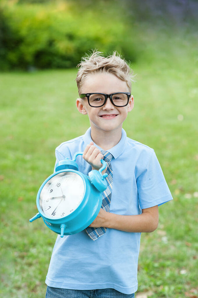 Portrait of a beautiful young school boy standing with big clock on the background autumn park. Farewell Bell. day of knowledge. beginning of the school year. - Фото, зображення