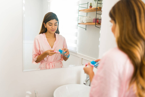 Yüzünü yıkamak ve temiz cilt bakımı rutini yapmak için makyaj çıkarıcı kullanan muhteşem bir genç kadının arka görüntüsü. - Fotoğraf, Görsel