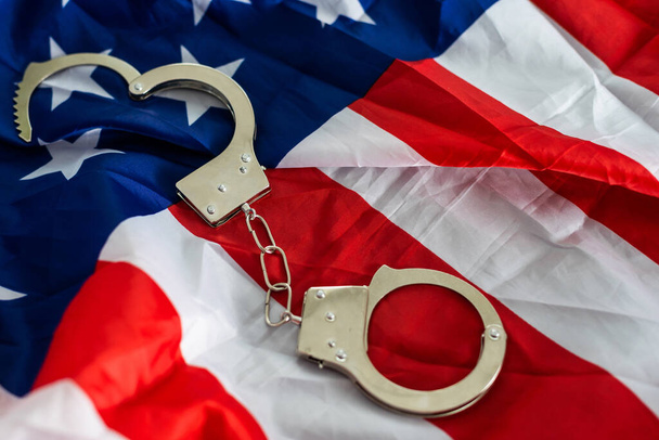 handcuffs on the background of the USA flag, the concept of crime in the United States of America. - Foto, immagini