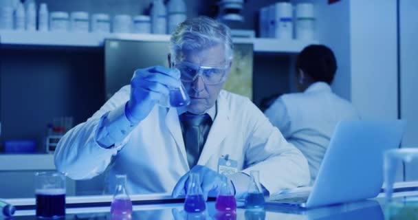 Experiment, science and chemistry work by a senior researcher, scientist or chemist inside a lab. Older man recording, researching and checking different formula, chemicals and samples in laboratory. - Video