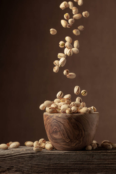 Flying salted pistachios. Dried nuts in a wooden bowl. Copy space. - Foto, immagini