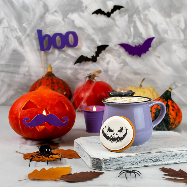 Halloween pumpkin and mug of coffee with cookies on the background of a gray wall with ghosts, bats, spiders, candles, pumpkins. leaves. Selective focus - Valokuva, kuva