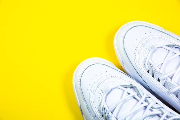 Modern sneakers on the yellow background. White leather trainers on big sole with spikes. Close up. - Photo, Image