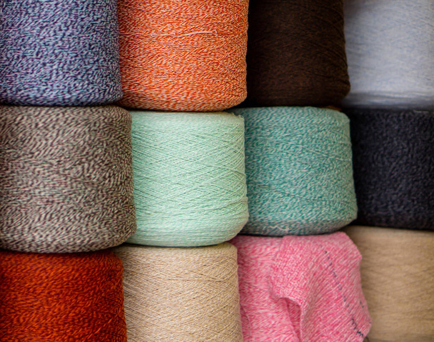 Multi-colored bobbins of yarn stacked on top of each other tightly stand side by side. Bright background. - Foto, Imagem