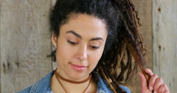 Closeup of a trendy, edgy and flirty woman with braided hair or dreadlocks, smiling with and happy expression. Headshot, face and portrait of funky, stylish and boho rocker against wood background. - Filmati, video