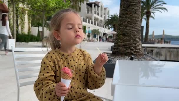Little girl eating ice cream licking a spoon. High quality FullHD footage - Video