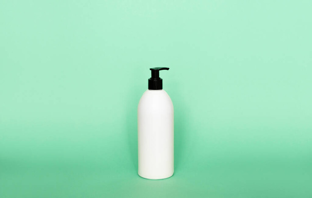 Liquid container for gel, lotion, cream, shampoo, bath foam. Cosmetic plastic bottle with dispenser pump on green background. Cosmetic packaging mockup with copy space - Foto, imagen