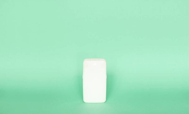 White plastic shampoo bottle isolated on green background. Skin care lotion. Bathing essential product. Shampoo bottle. Bath and body lotion. Fine liquid hand wash - 写真・画像